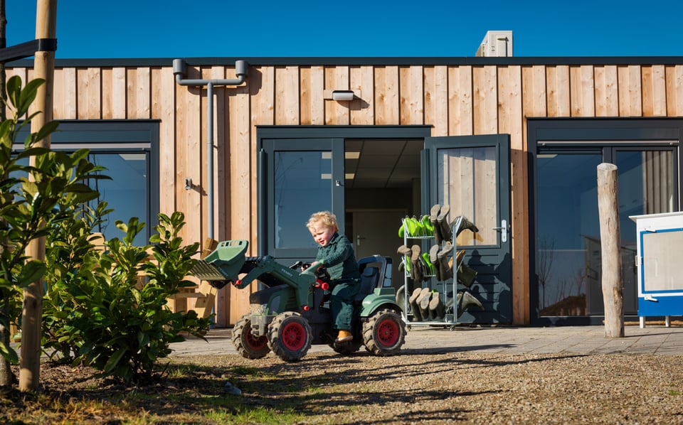 kindje op speelgoed tractor bij een modulair kinderdagverblijf